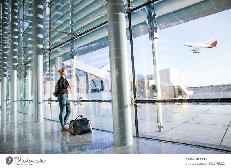 Junge Frau wartet am Flughafen und schaut durch das Fenster. Ferien & Urlaub & Reisen Tourismus Abenteuer Business Telefon Handy PDA Technik & Technologie