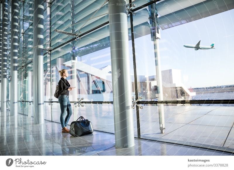 Junge Frau wartet am Flughafen und schaut durch das Fenster. Ferien & Urlaub & Reisen Tourismus Abenteuer Business Telefon Handy PDA Technik & Technologie