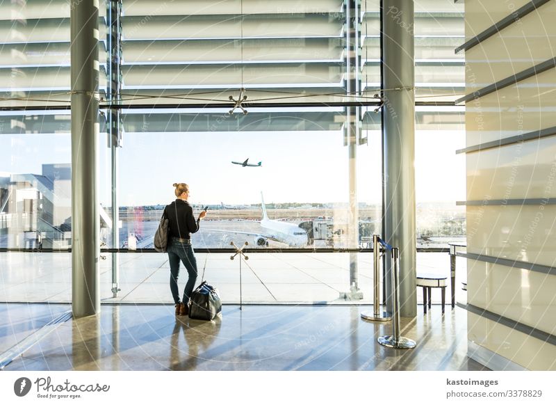 Junge Frau wartet am Flughafen und schaut durch das Fenster. Ferien & Urlaub & Reisen Tourismus Abenteuer Business Telefon Handy PDA Technik & Technologie