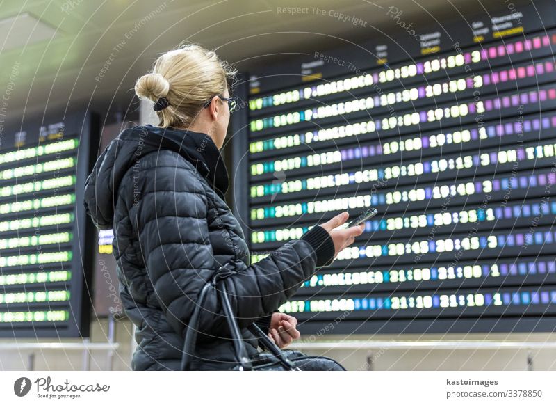 Frau am Flughafen, die auf die Fluginformationstafel schaut. Ferien & Urlaub & Reisen Tourismus Ausflug Winter Dekoration & Verzierung Telefon PDA Luftverkehr