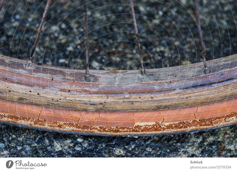 Alte Fahrradfelge aus Holz mit Holzwurmlöchern Nahaufnahme Metall Kunststoff alt Verfall Vergänglichkeit Felge Detailaufnahme Gummi Wurmloch altehrwürdig