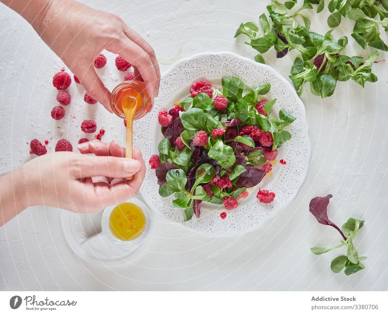 Person, die Himbeersaft in Obstsalat tut Himbeeren Salatbeilage Spinat Saft geschmackvoll organisch Löffel lecker natürlich frisch Lebensmittel Beeren