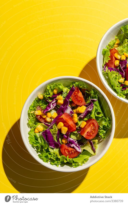 Frischer Kopfsalat mit Kirschtomaten Salatbeilage Lebensmittel Salatkopf Mais rote Zwiebel Sonnenlicht frisch Gemüse Veganer Vegane Ernährung gesunde Ernährung