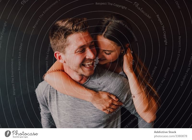 Fröhliches Paar amüsiert sich beim gemeinsamen Entspannen nach dem Training im dunklen modernen Fitness-Studio Lachen sich[Akk] entspannen Spaß heiter Huckepack