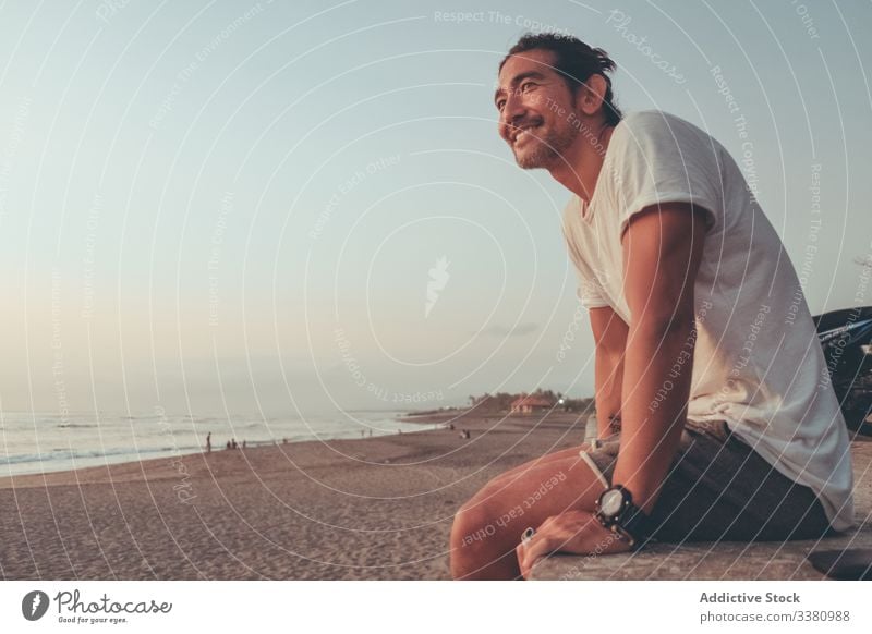 Glücklicher Mann mit Motorrad genießt Sonnenuntergang am Strand sich[Akk] entspannen genießen MEER Meer sitzen männlich heiter positiv lässig ruhen Lifestyle