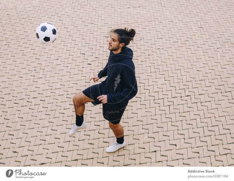 Sportler, der einen Fussball mit dem Knie kickt Mann Fußball Ball Kick Straße Straßenbelag Training Aktivität männlich Spiel Sportbekleidung Spieler Athlet