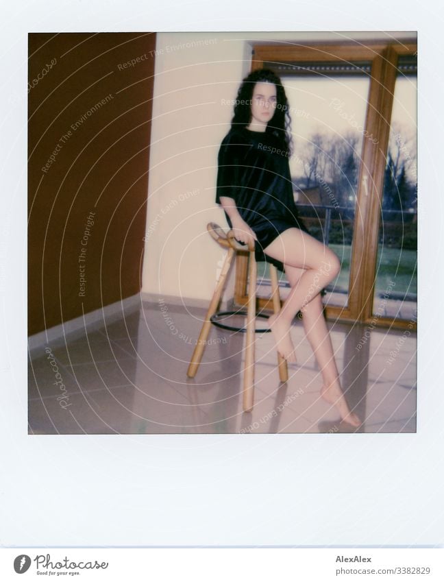 Analoges Polaroid- Portrait einer jungen Frau vor Balkonfenster Blick in die Kamera Porträt Zentralperspektive Schwache Tiefenschärfe Kunstlicht Tag