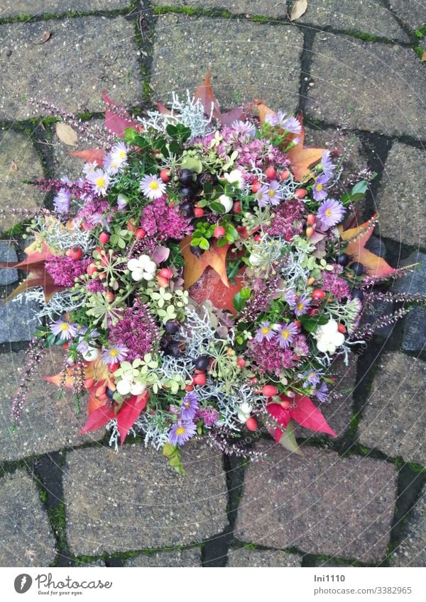 Blumenkranz mit frischen Herbstblumen liegend in Schale auf Pflastersteinen Astern herbstdekoration Tischschmuck selbstgemacht Heidekraut Fetthenne Knallerbsen