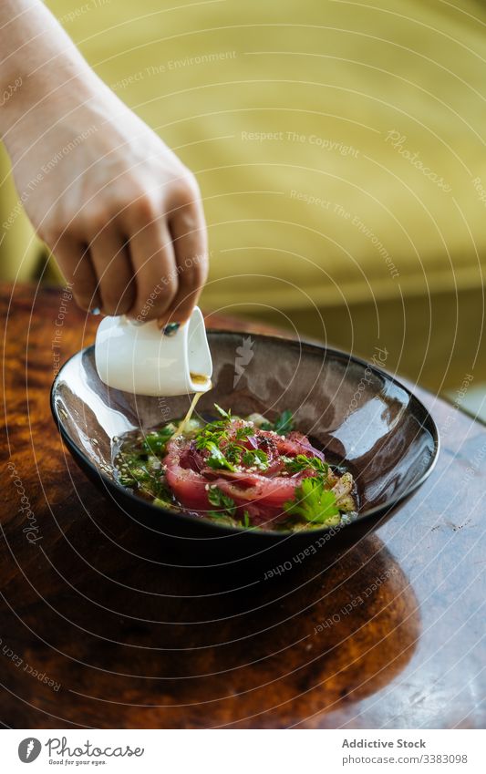 Person, die Sauce auf einem Teller in den Salat gießt Salatbeilage Gemüse Saucen Gießen Koch vorbereiten dienen frisch geschmackvoll lecker Küche Feinschmecker