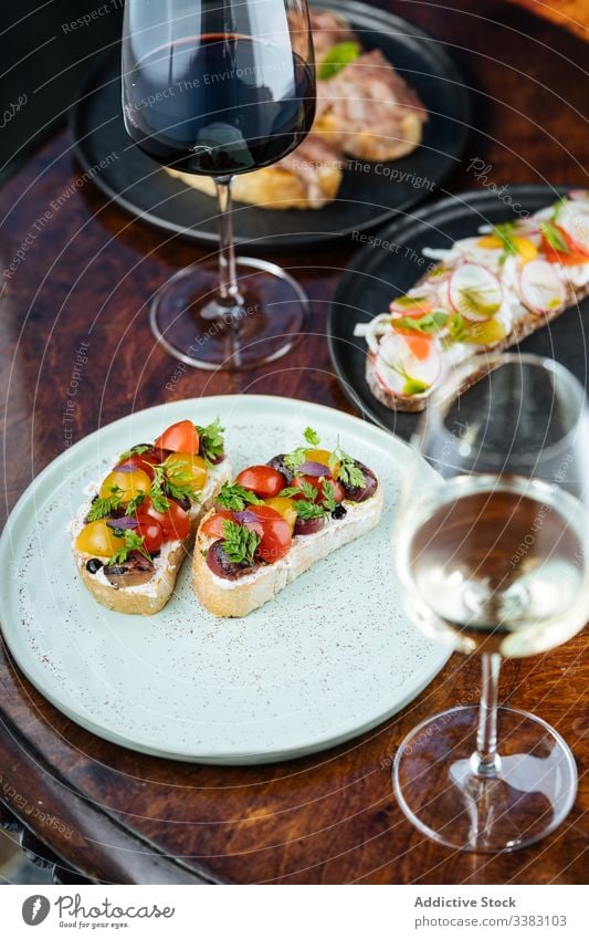 Sandwiches mit Kirschtomaten auf Brot auf Tisch mit Wein Tomaten Kirsche Belegtes Brot Zuprosten Glas lecker Lebensmittel geschmackvoll Feinschmecker Getränk