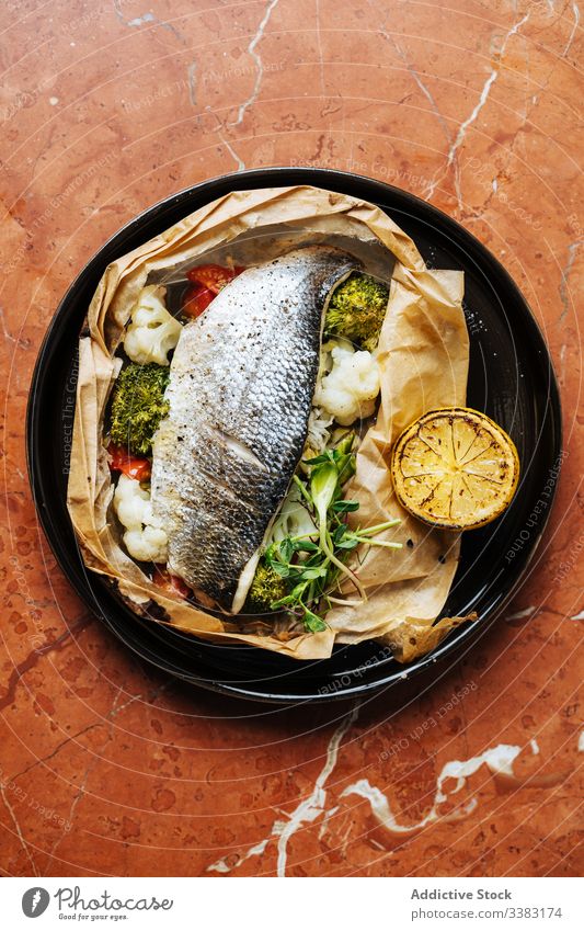 Schmackhaftes gebackenes Fisch- und Gemüsegericht im Restaurant Haute Cuisine Zitrone Brokkoli Blumenkohl Kraut Teller Tisch Meeresfrüchte lecker Mahlzeit