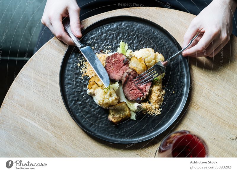 Person, die zum Essen Roastbeef mit Gemüse isst Vanillerostbraten Chip Abendessen Rindfleisch Scheibe Gastronomie Blumenkohl Besteck Restaurant Sahne Saucen