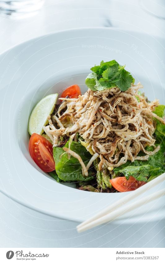 Stilvoll servierter bunter Salat mit Fleisch im Restaurant Salatbeilage Gemüse Grün Haute Cuisine farbenfroh Tomate Kalk Essstäbchen Petersilie Gesundheit