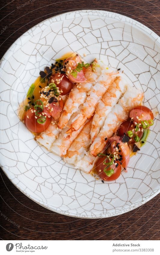 Appetitanregende Meeresfrüchte mit Tomaten und Kräutern auf einem Zierteller Granele Kraut Sesam Samen Lebensmittel geschmackvoll frisch lecker Feinschmecker