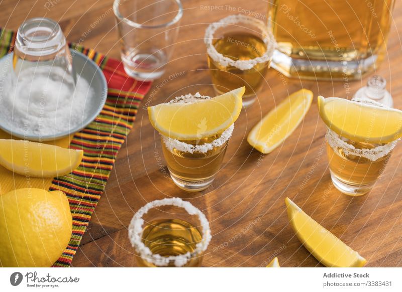 Tequila in Shots mit Salzrand und Zitrone Alkohol Schuss Rand Schnaps Tisch hölzern Glas Getränk trinken frisch geschmackvoll Zitrusfrüchte orange Party lecker