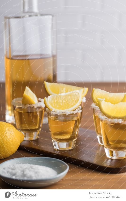 Tequila in Shots mit Salzrand und Zitrone Alkohol Schuss Rand Schnaps Tisch hölzern Glas Getränk trinken frisch geschmackvoll Zitrusfrüchte orange Party lecker