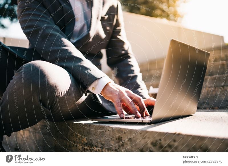 Lächelnder junger Geschäftsmann sitzt auf der Treppe mit Laptop und Kaffee. Erwachsener Vollbart bärtig Business Kaukasier Großstadt Computer Konzept Anschluss