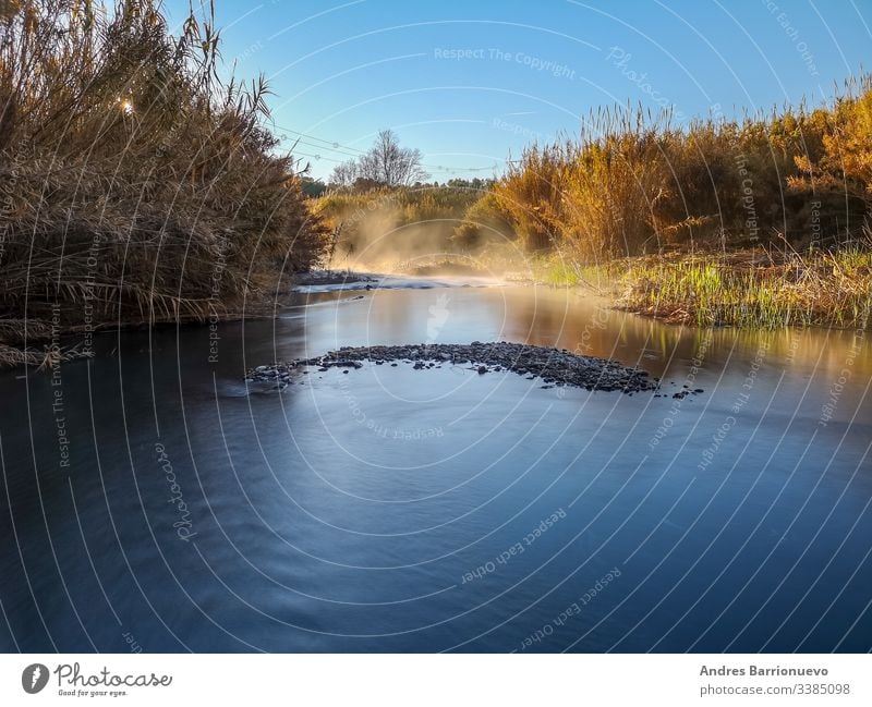 Fluss mit Verdunstung an einem sehr kalten Morgen Sonne Frühling Stein Himmel Hintergrund Tag Waldfluss Natur Gras Ansicht Flusswassersteine wild