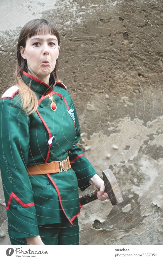 teenager steht vor mauer mit uniform und hammer in der hand Fotochallenge Jugendliche Teenager Mauer Wand Uniform Hammer Werkzeug Gesicht Grimasse Kostüm