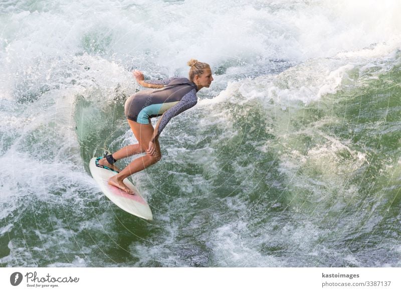 Attraktives, sportliches Mädchen surft auf der berühmten künstlichen Flusswelle im Englischen Garten, München, Deutschland. Surfer Brandung Surfbrett Surfen