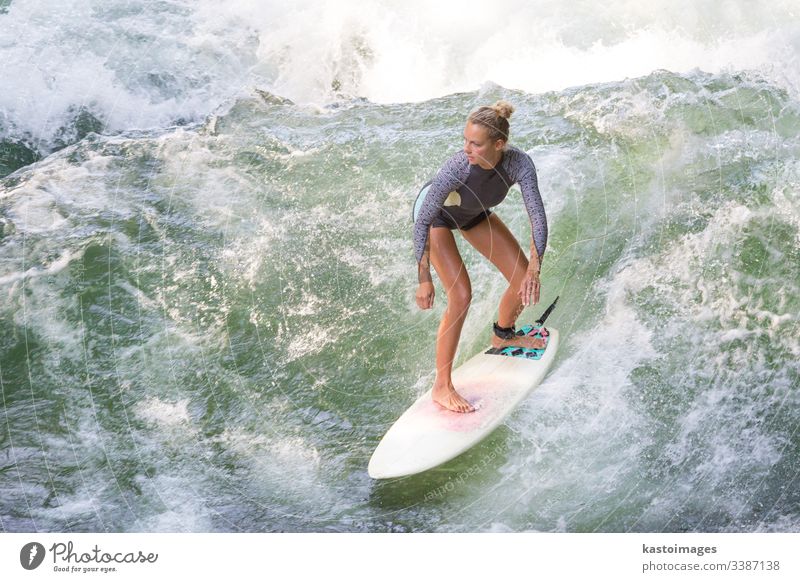 Attraktives, sportliches Mädchen surft auf der berühmten künstlichen Flusswelle im Englischen Garten, München, Deutschland. Surfer Brandung Surfbrett Surfen