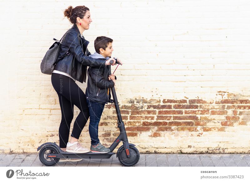 Mutter und Sohn auf einem Elektroroller aktiv Junge lässig Kind Großstadt Tag E-Roller Öko elektrisch Europa Familie Frau Spaß Generation Kick Kickroller