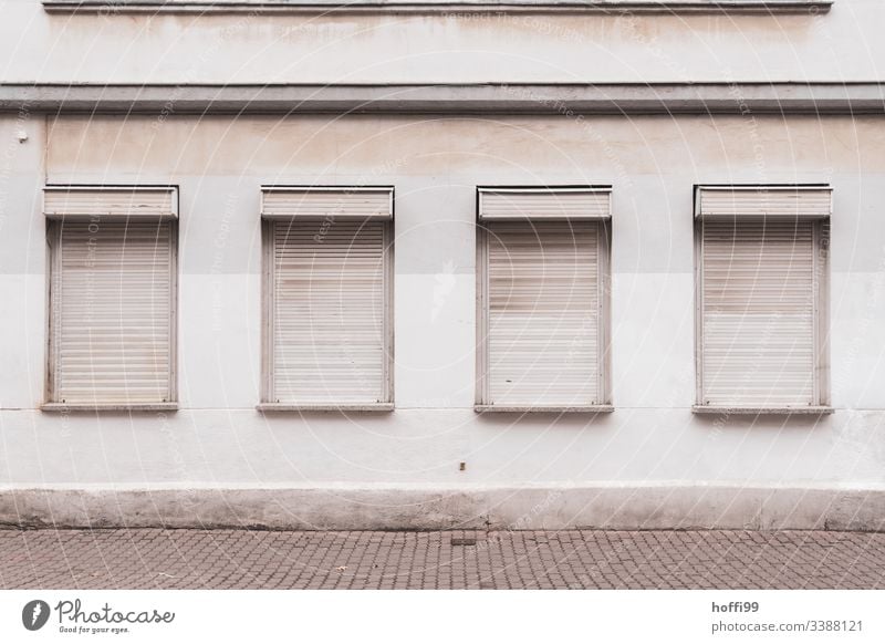 trostlose Außenfassade mit geschlossenen Jalousien grau trist Tristesse jalousinen Rollladen graue Wand schmucklos Einsam Depression depressivität Verlassen