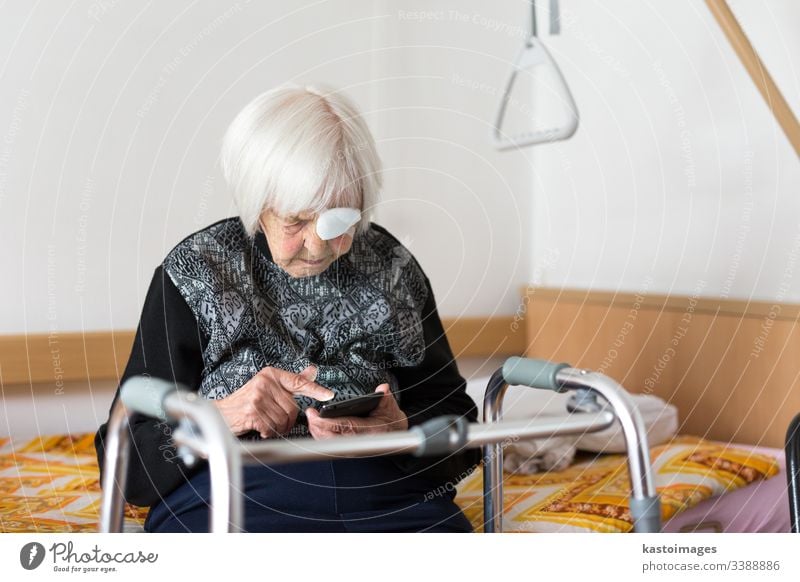 Einsame ältere Frau, 95 Jahre alt, die mit einem modernen Mobiltelefon am Schlechten sitzt. Senior Rentnerin Pflege Behinderung Krankenhaus Mobilität heimwärts