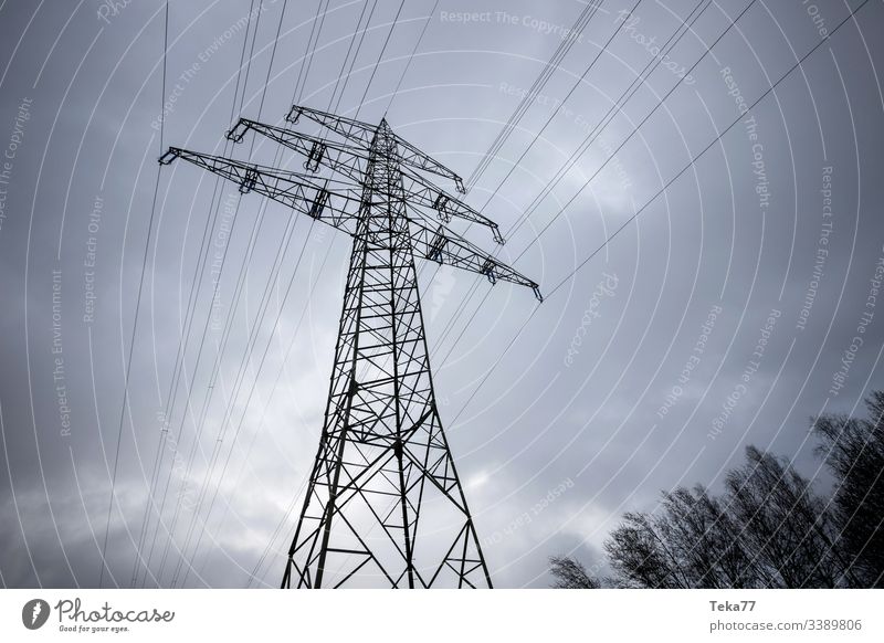 ein Strommast am Winterhimmel Elektrizität Energie Kabel Hochspannung Energie-Transport Volt ampstorm Sonne Blitze Kraftwerk Stromkabel Farben Himmel blau weiß