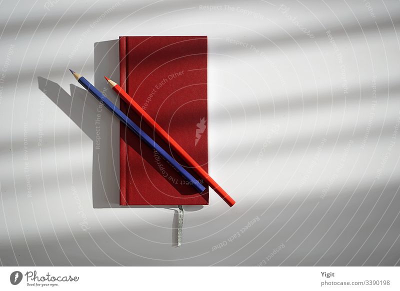 Stilleben mit rotem Hardcover-Notizbuch und Stiften Vogelperspektive Hintergrund neutral Textfreiraum rechts Menschenleer Nahaufnahme Farbfoto Studioaufnahme