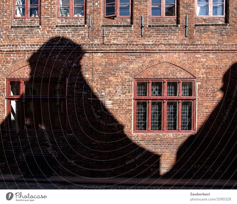 Fassade aus roten Backsteinen mit Fenster und Schatten eines gegenüberliegenden Hauses Wand ziegelrot Bauwerk Stein Textfreiraum unten Kontrast historisch