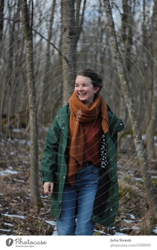 Frau steht im Wald und lacht Bäume Wolken Mantel Schal hemdbluse Jeanshose gepunktet atmen Gürtel ockerfarben Grün Außenaufnahme Farbfoto Tag feminin Auszeit