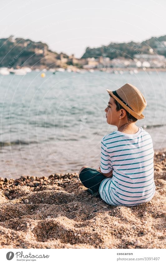 Kleiner Junge mit Hut, der am Strand auf das Meer schaut Rücken Hintergrund schön blau Kind Kindheit Kinder Küste Kontemplation niedlich genießend Mode modisch