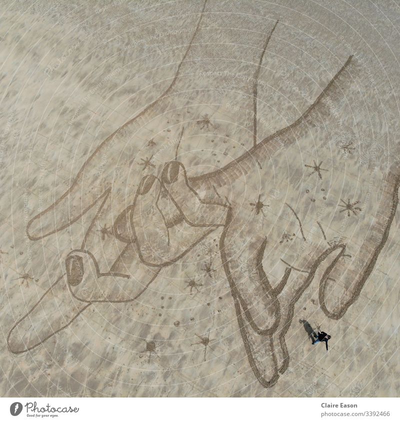 Riesige Sandkunstzeichnung mit einer Person, die die Hand hält; mit einer Dji-Kamera erstellt Riese Hände Händchenhalten Romantik Natur Umwelt Küste Strand