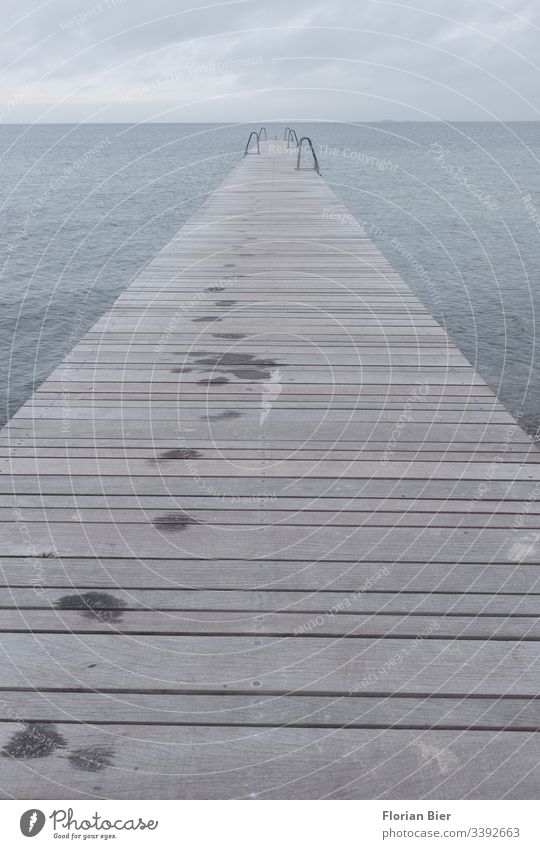 Nasse Fußspuren auf eime Langer Steg mit Badeleitern bei trübem Wetter nass Meer Holzlatten Baden Leiter Wolken regen lang gealtert stabil Wasser See