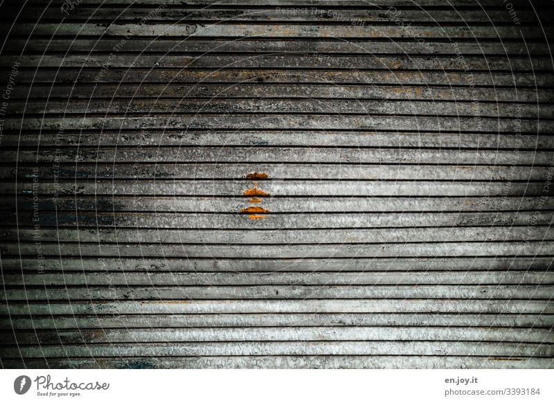 Geschlossenes Garagentor mit einem Rost Fleck Lagerhalle Gebäudeteil Industrie Fabrik Tor Einfahrt Aluminium Schmutz Alt Rollladen Licht Schatten Muster Dreck