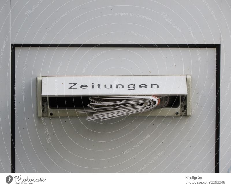 Tageszeitung in einem Haustürbriefkasten mit der Beschriftung Zeitungen steckend Briefkasten Briefkastenschlitz Außenaufnahme Farbfoto Menschenleer Tür