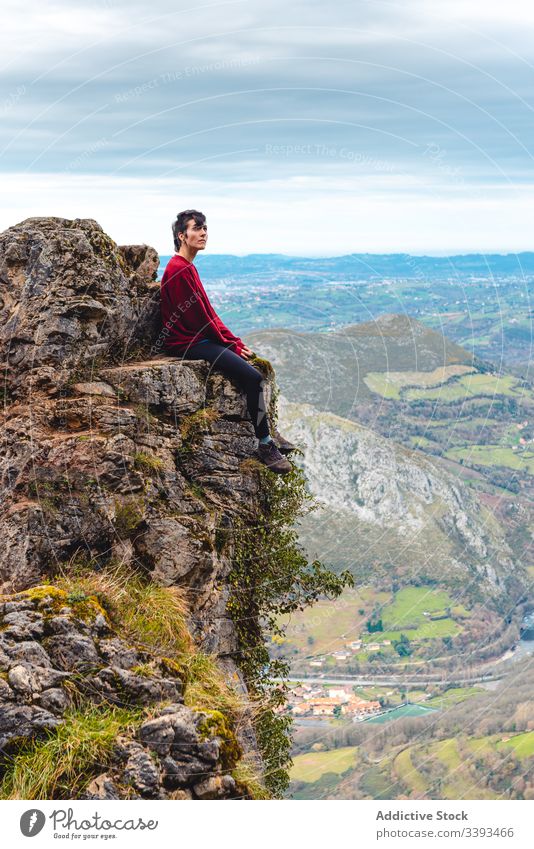 Reisender genießt Landschaft, während er am Rande eines Felsens gegen nebliges Hochland sitzt Klippe Berge u. Gebirge Trekking Aussichtspunkt Freiheit Höhe Saum