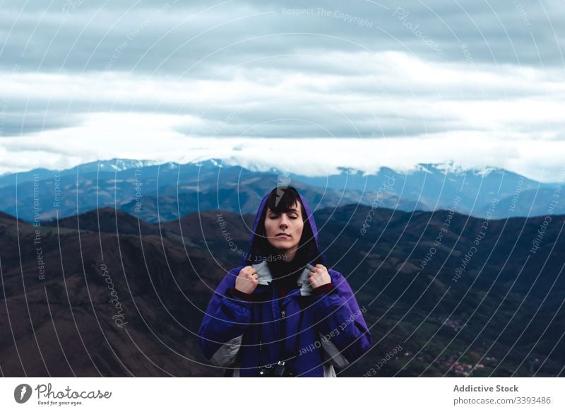 Touristin in violetter Jacke mit Rucksack mit geschlossenen Augen in malerischen Gebirgskämmen beim Stehen in Monsacro reisen Berge u. Gebirge Tourismus