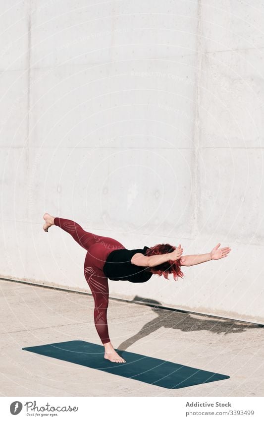 Frau macht Gleichgewichtsübung in Baumhaltung während sie Yoga auf der Straße praktiziert Athlet üben Training Übung Dehnung Barfuß Beton Windstille passen