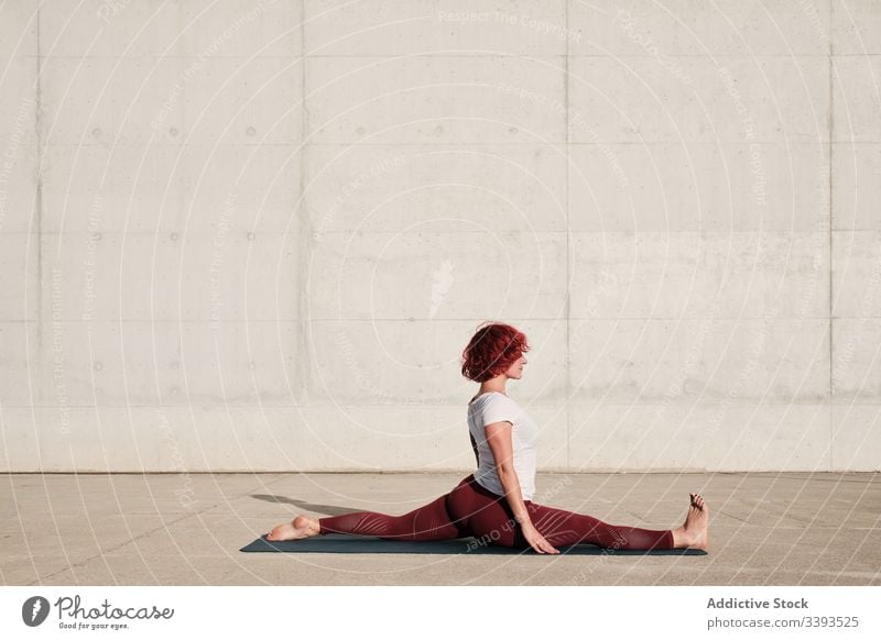 Flexible junge Sportlerin, die auf der Straße Yoga praktiziert beweglich Übung Dehnung Frau akrobatisch üben Training gymnastisch Schatten physisch urban