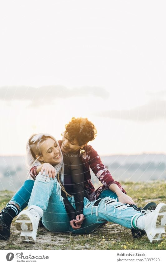 Zufriedene weibliche Teenager, die sich auf Gras umarmen Frauen Freundin Lachen Spaß Umarmung Natur Wiese bester Freund Umarmen Lächeln genießen teilen lässig