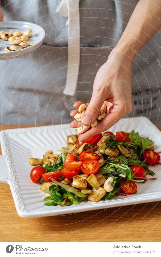 Frau garniert Salat mit Nüssen Lebensmittel Essen zubereiten Salatbeilage Rezept Cashewnuss Muttern Gemüse Bestandteil Garnierung Küche Gesundheit Mahlzeit