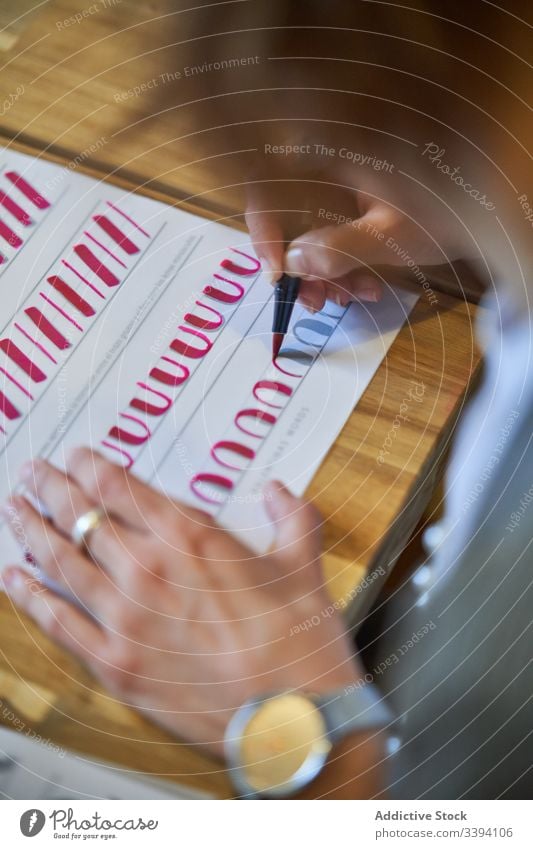 Gesichtslose Frau lernt Schriftzug bei Tisch Beschriftung zeichnen Papier Handschrift Beruf Schreibtisch Arbeitsplatz Kunst kreativ Handwerk graphisch Bildung