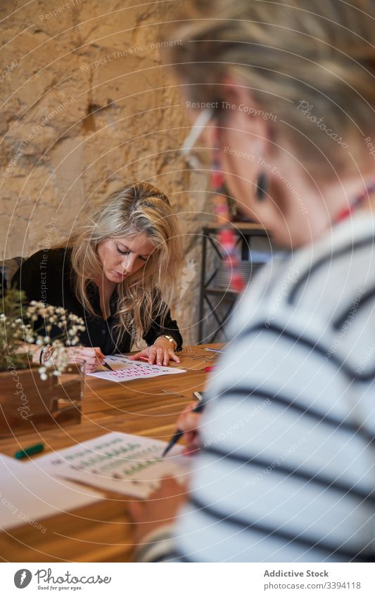 Künstlerin zeichnet mit Bleistift im Kunstatelier Frau Beschriftung Handschrift zeichnen Konzentration kreativ Fokus Lifestyle lernen Job sitzen Skizze