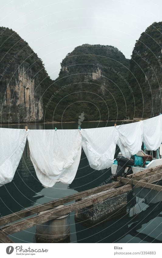 Weiße Wäsche auf einer Wäscheleine in einem schwimmenden Dorf in der Halong Bucht in Vietnam Bettlaken Floating Village schwimmendes Dorf Kalksteinfelsen