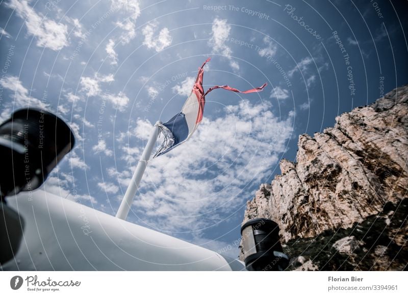 Französische Flagge im Wind auf einem Boot Frankreich Fahne Himmel Wolken Berge Klippe maritim Fahnenstange Sommer Sonne rot weiß blau Signallampe wehen