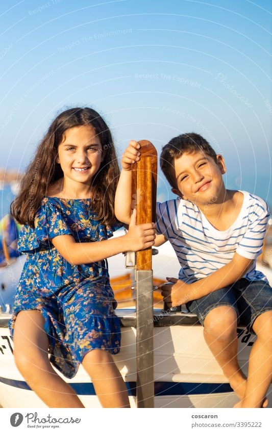 Porträt von zwei kleinen Kindern, die am Strand in ein Fischerboot geklettert sind Abenteuer blau Holzplatte Boot Junge Brüder Kapitän Kindheit Küste