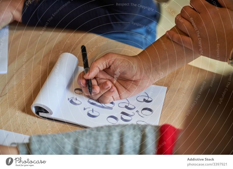 Gesichtslose Frau lernt Schriftzug bei Tisch Beschriftung zeichnen Papier Handschrift Beruf Schreibtisch Arbeitsplatz Kunst kreativ Handwerk graphisch Bildung