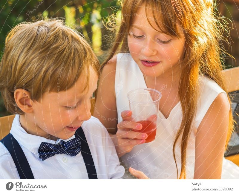 Elegante Kinder entspannen sich bei einer Hochzeit Mädchen Junge Glück herumhängen Pause anhaben elegant Kleidung Ringträger Sommer Geschwister spielen Natur